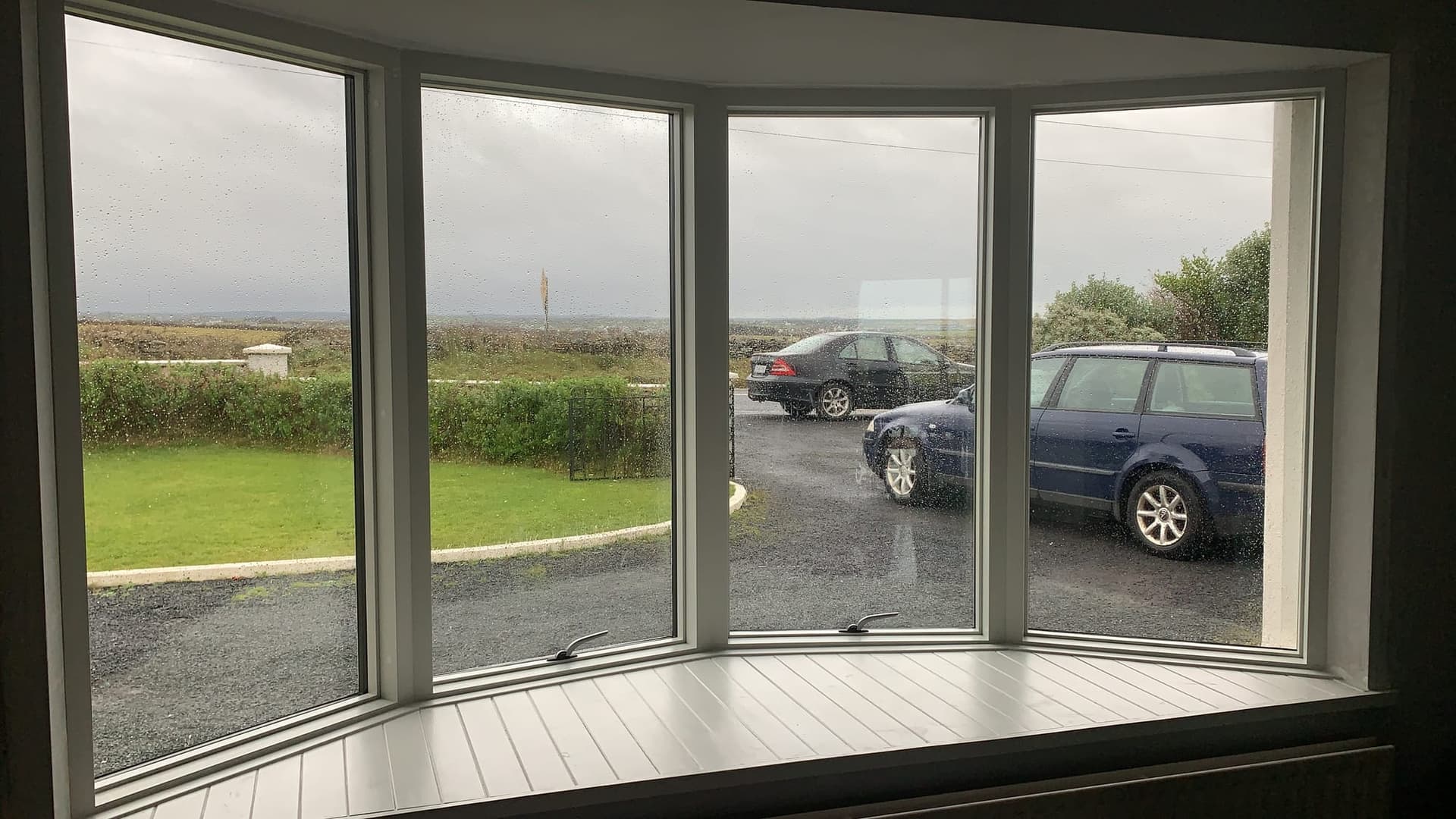 White-framed bay window with a built-in window seat looking out over the garden, by MDM Windows & Doors